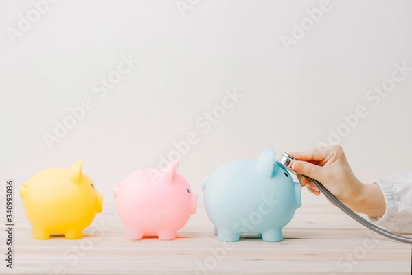 Fototapeta Doctor using stethoscope to check 3 piggy bank in queue. Concept check saving money and financial sustainability