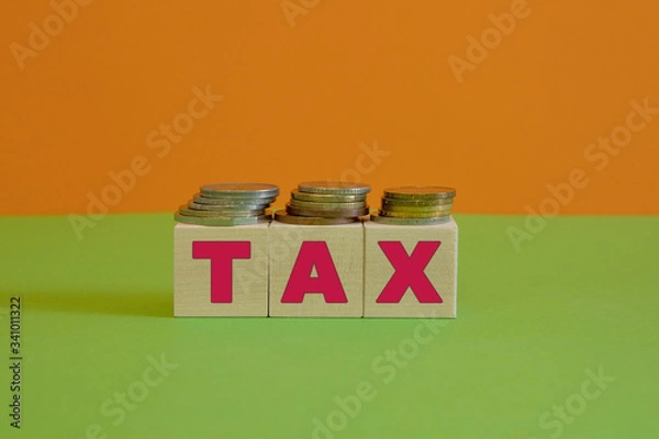 Fototapeta Rows of coin stacks with toy blocks symbolizing taxation.