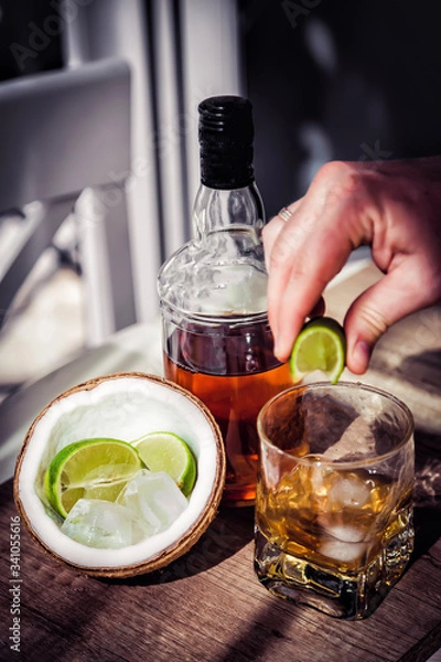 Fototapeta Rum with ice and coconut, a bottle of rum with lime