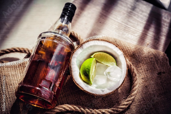 Fototapeta Bottle of rum with lime ice and coconut, coconut glasses and rum