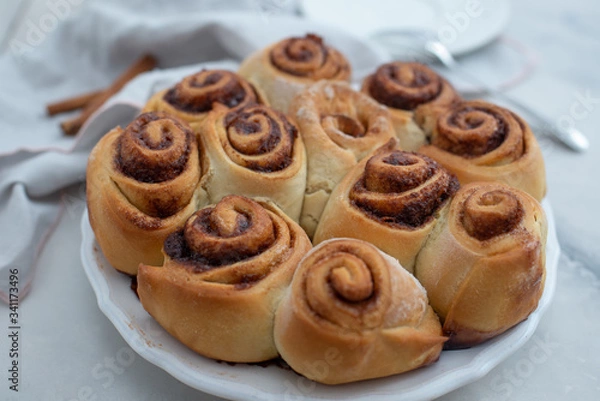 Fototapeta Cinnamon rolls with sugar frosting. With cinnamon sticks and spices