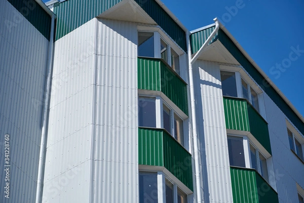 Fototapeta facade of a new multistory building with white and green metal siding, many Windows