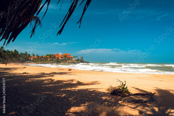 Obraz Piękna tropikalna plaża, ocean i fale na tle błękitnego nieba.