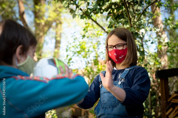 Fototapeta Two children with a face mask playing ball