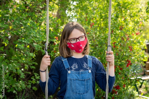 Obraz Child with face mask is sitting on a swing