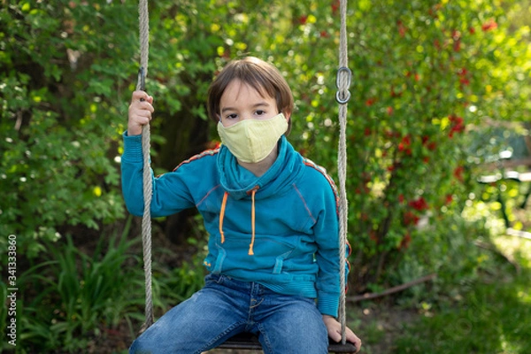 Obraz Child with face mask is sitting on a swing