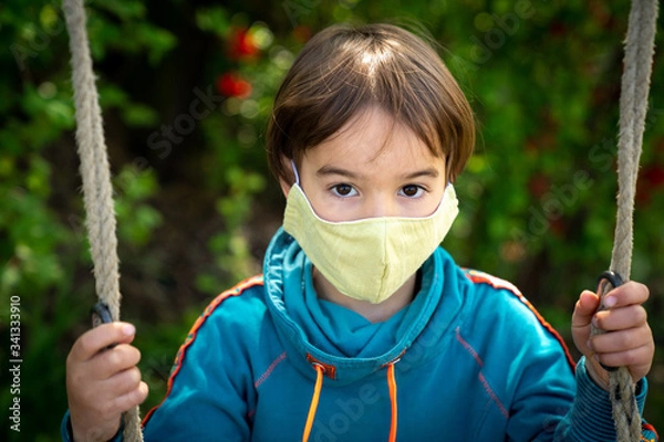 Obraz Child with face mask is sitting on a swing