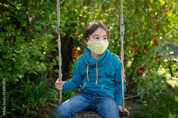 Obraz Child with face mask is sitting on a swing
