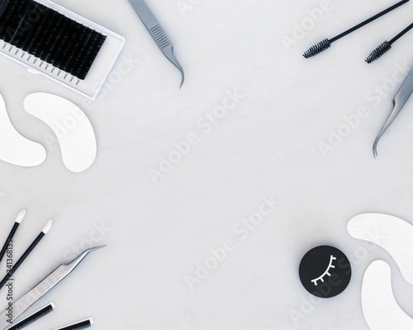 Fototapeta Produkty do przedłużania rzęs, w tym łyżka do rzęs, pęseta, płatki pod oczy i szczoteczki. Produkty są w stylu flat lay na jednolitym białym tle z przestrzenią pośrodku ramy