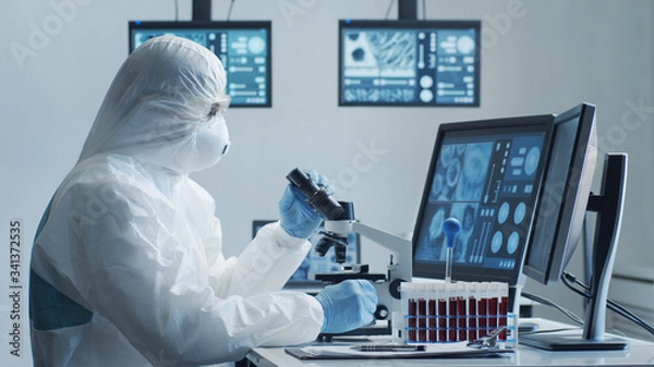 Fototapeta Scientist in protection suit and masks working in research lab using laboratory equipment: microscopes, test tubes. Coronavirus 2019-ncov hazard, pharmaceutical discovery, bacteriology and virology.