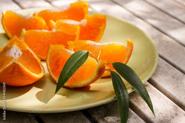 Obraz Fresh orange served outside in garden on white table  in sun lights close up
