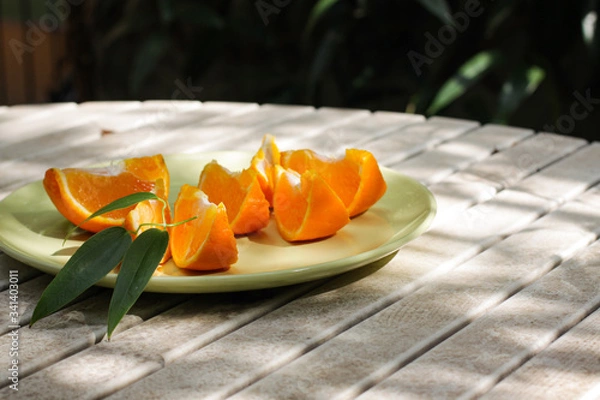 Obraz Fresh orange served outside in garden on white table  in sun lights close up