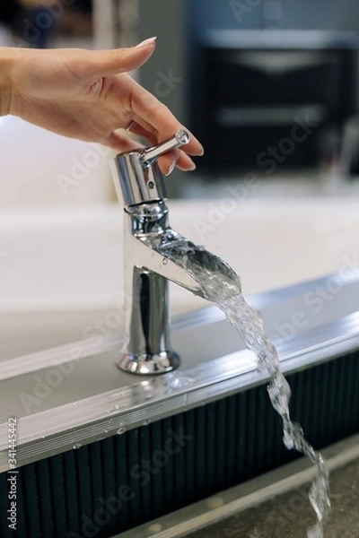 Fototapeta hand close water tap. Open chrome faucet washbasin