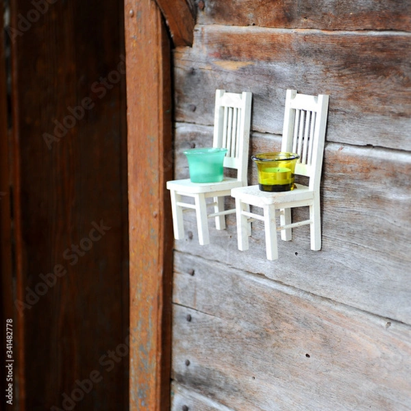Obraz Small decorative chairs on the wall serve as candlesticks.