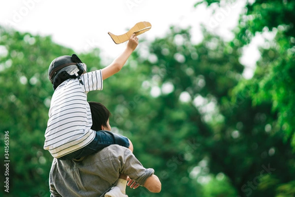 Fototapeta Father and son on his shoulder playing paper plane, spending time together at fresh green park in afternoon sunlight, the concept of family outdoor, daddy hero, Family background. Single Daddy and son