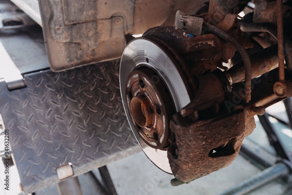 Fototapeta change the old drive to the Brand new brake disc on car in a garage. Auto mechanic repairing .