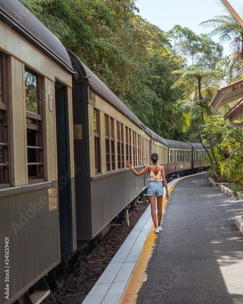 Fototapeta Woman & Kuranda Scenic Railway Train. Tourist train journey across rainforest and jungles in Cairns Australia. Train, train tracks, passenger seats, interior, skyrail, bridge, mountains, landscape.