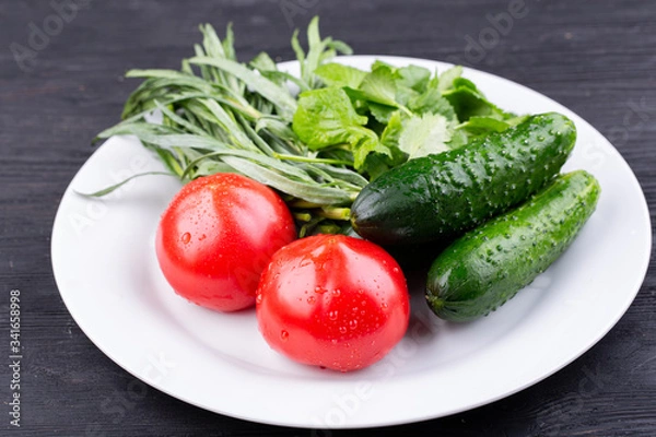 Fototapeta Plate with vegetables fresh, tomatoes and cucumbers with greens