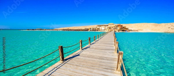 Fototapeta Wooden Pier at Orange Bay Beach with crystal clear azure water and white beach - paradise coastline of Giftun island, Mahmya, Hurghada, Red Sea, Egypt.