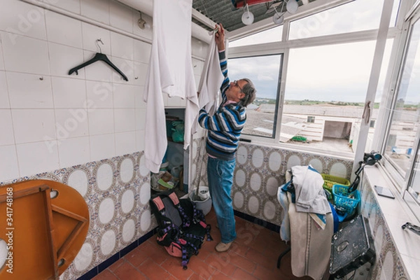 Obraz Senior man hanging clothes.