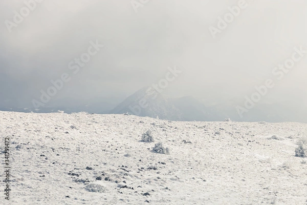 Obraz Beautiful, abstract, soft view of snow covered mountain highlands and distant rocky peak barely visible through the fog