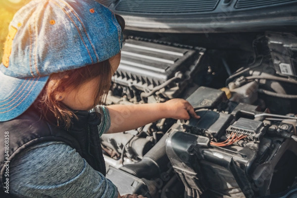 Fototapeta Little child trying to fix broken real car. Dreaming to be auto technician. View from the back