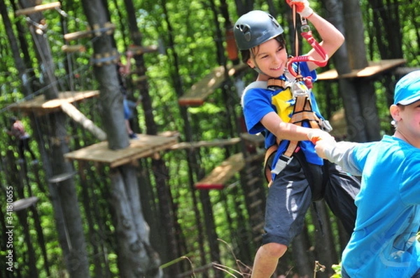 Fototapeta Summer camp. Radość dziecka podczas zabawy z innymi dziećmi w parku linowym na obozie sportowym letnim