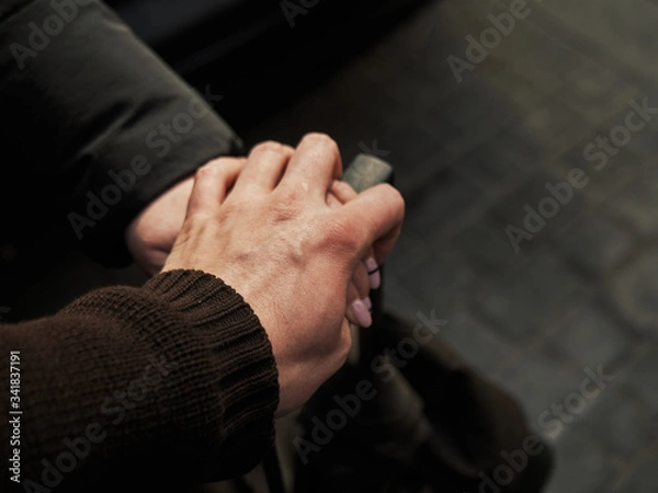 Fototapeta Two hands of people in love on the handle of a suitcase, traveling together