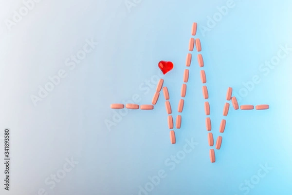 Obraz Pills in shape of cardiogram pulse on blue gradient background. Vitamins and red glass heart, symbol of healthy lifestyle. Pharmaceutical and cardiology concept. Heartbeat rhythm made of tablets