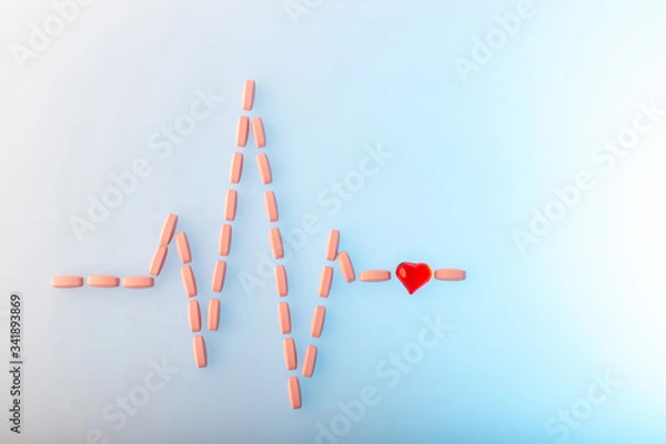 Obraz Pills in shape of cardiogram pulse on blue gradient background. Vitamins and red glass heart, symbol of healthy lifestyle. Pharmaceutical and cardiology concept. Heartbeat rhythm made of tablets