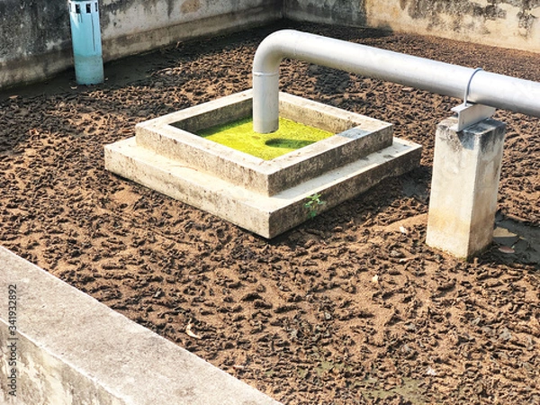 Fototapeta Sludge treatment in wastewater management system, flowing brown smelly liquid and drying in sludge bed, made it for fertilization can use in agriculture field. Cement and concrete well background.