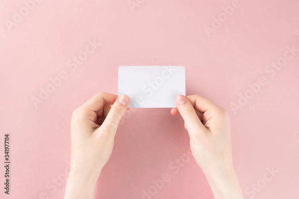 Fototapeta Female hand holding white business card on colorful pink background. Template, mockup, blank for web, social media, advertisement with copy space. Marketing, business branding. Stock photo.