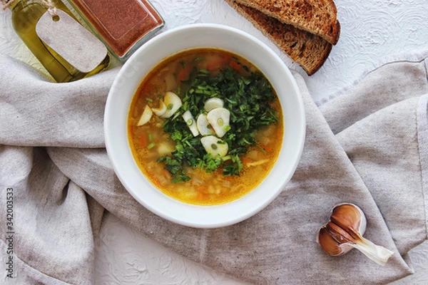 Obraz Lentil soup with garlic and herbs in a white bowl on the table. Diet, home-cooked food.