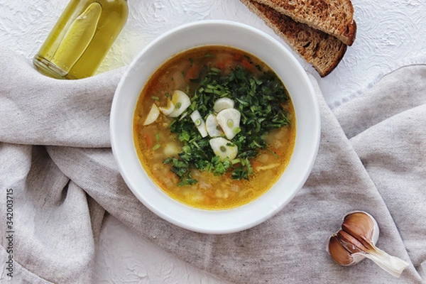 Obraz Lentil soup with garlic and herbs in a white bowl on the table. Diet, home-cooked food.