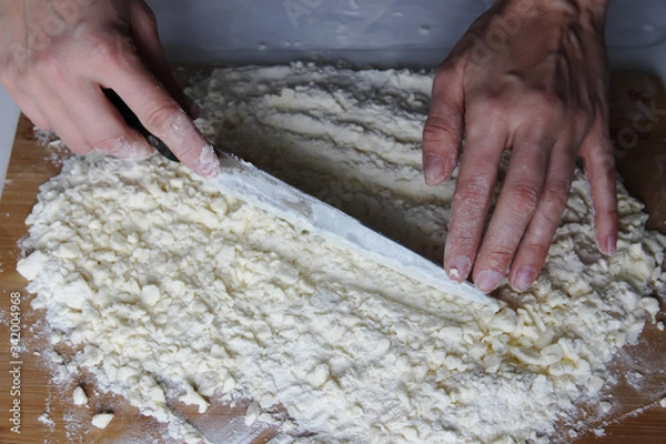 Obraz The cook's hands chop butter and flour on a wooden Board with a knife. Homemade cake. Housework.