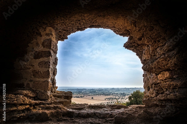 Fototapeta View on the coast through the hole of an ancient wall