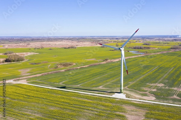 Fototapeta Windmill on a background of green field. Green electricity production. Alternative energy.
