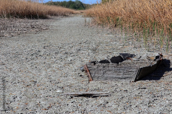 Fototapeta old sunken boat appears in a river bed that has dried up due to drought