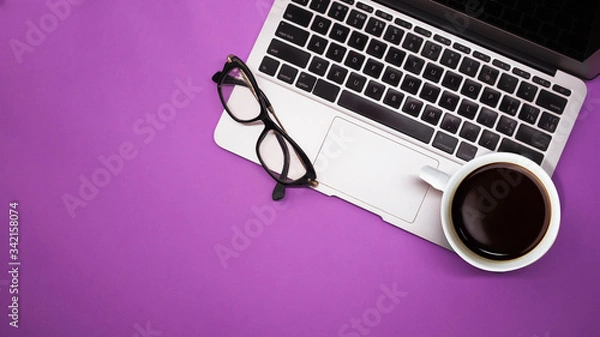 Fototapeta gray laptop with  cup of coffee and glasses on purple background table, working place at home or in the office