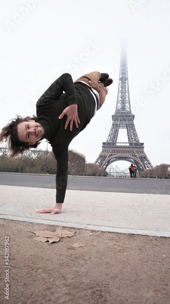 Fototapeta a young handsome man doing a handstand in Paris in front of tower ,traveling lifestyle