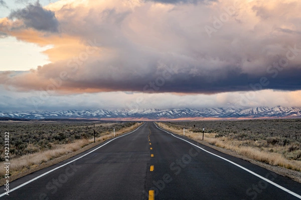 Fototapeta Road leading through the landscape towards snowy mountains and cloud