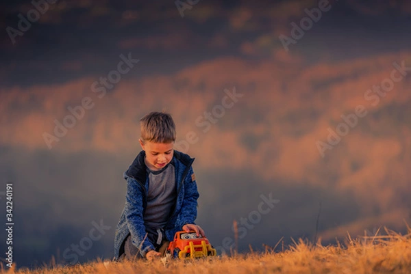 Fototapeta A small child plays with a car