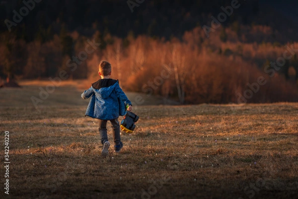 Fototapeta A small child plays with a car