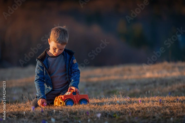 Fototapeta A small child plays with a car