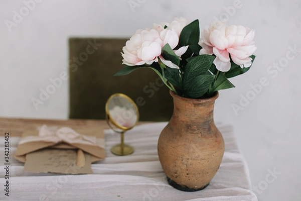 Fototapeta Romantic dressing table with a bouquet of peonies in a vase and a mirror. Bedroom interior in the vintage style. Boudoir. 