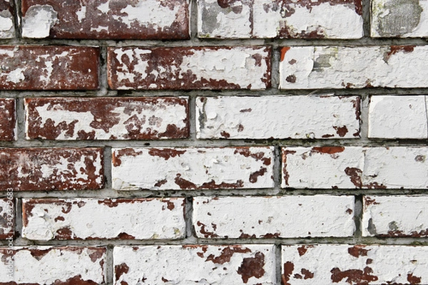 Fototapeta Wall from old and peeling brick, full frame use for the background. Shabby and faded white paint on a brick wall