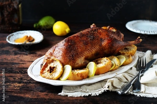 Obraz Traditional baked duck with apples and lemon on a dark wooden table, rustic style