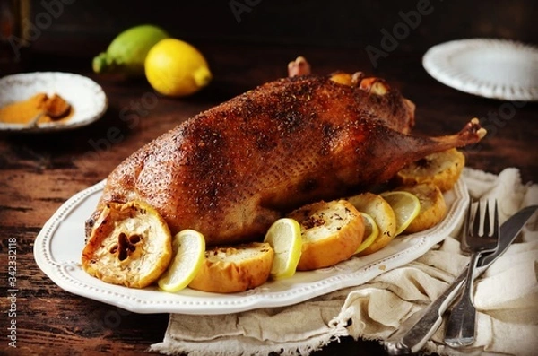 Obraz Traditional baked duck with apples and lemon on a dark wooden table, rustic style