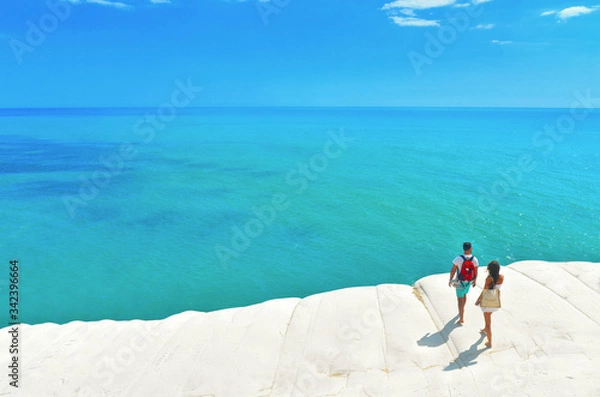 Fototapeta white cliffs naturally made of smooth pug at Scala dei Turchi beach with group of young people with turquoise mediterranean sea and blue cloudy summer sky near Agrigento, Sicily, Italy