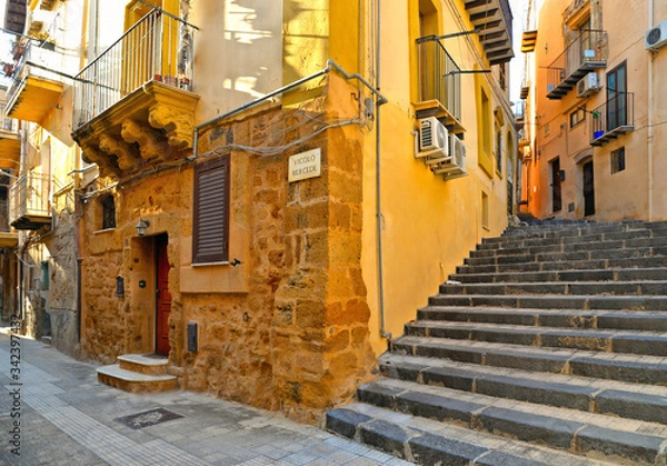 Fototapeta View of a narrow street with steps, old buildings and facades in the historical city of Agrigento in Sicily, Italy